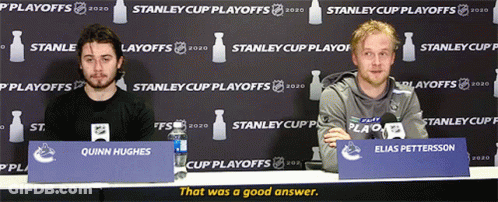 Two Men At Table With Quinn Hughes Sign GIF
