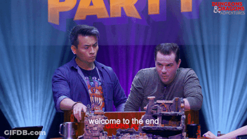 Two Men At Table With Welcome To The End Sign GIF