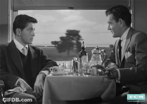 Two Men At Table With Wine Bottle And TCM Logo GIF