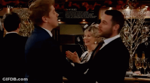 Two Men Beside ITV Sign GIF