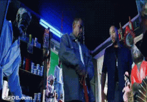Two Men By Shelf Full Of Bottles GIF