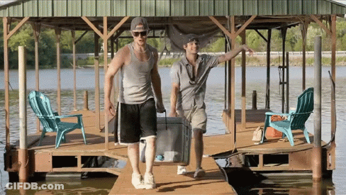 Two Men Carrying Cooler On Dock GIF