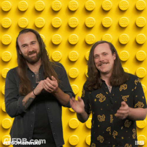 Two Men Clapping On Yellow Background With Lego Bricks GIF
