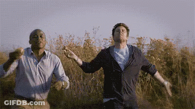 Two Men Dancing In A Field With Arms Outstretched GIF