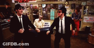 Two Men Dancing In Front Of A Help Wanted Sign GIF