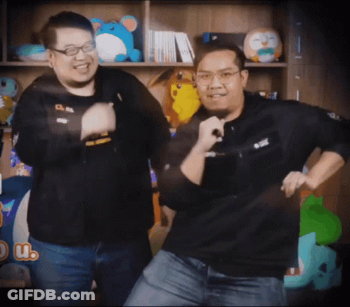 Two Men Dancing In Front Of Bookshelf With A Patch On Jacket GIF