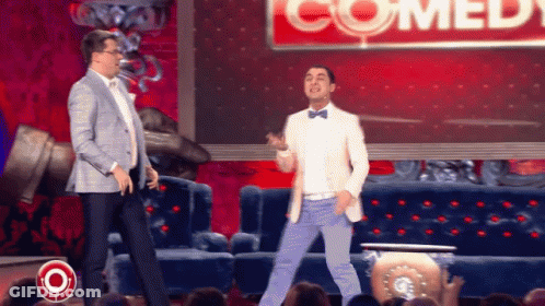 Two Men Dancing In Front Of Comedy Sign GIF