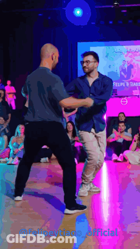 Two Men Dancing In Front Of Felipe Tiago Screen GIF