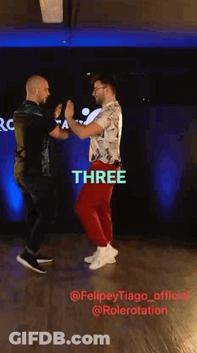 Two Men Dancing In Front Of Sign Saying Three GIF