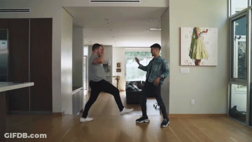 Two Men Dancing In Living Room With Painting GIF