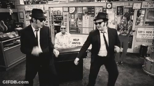 Two Men Dancing In Store With Help Wanted Sign GIF