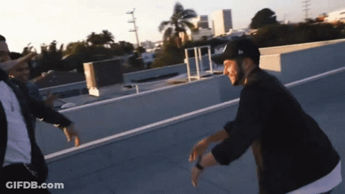 Two Men Dancing On Rooftop One Wearing New Era Hat GIF