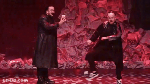 Two Men Dancing On Stage With Pile Of Money GIF