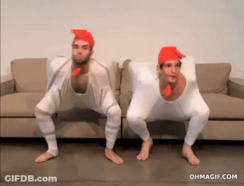 Two Men Dressed As Chickens Squatting On Couch GIF