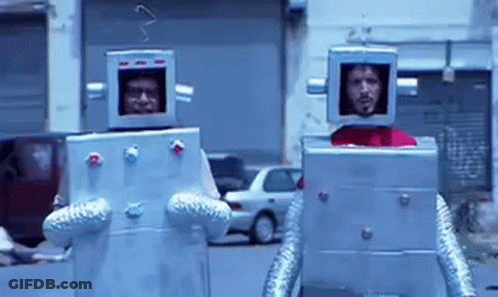 Two Men Dressed As Robots Walking Down Street GIF