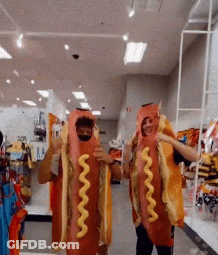Two Men Dressed Up As Hot Dogs With Mustard On Them GIF