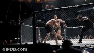 Two Men Fighting In Cage With Crowd And Referee GIF