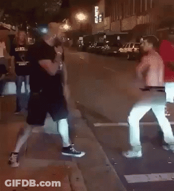 Two Men Fighting On Sidewalk In Front Of Building GIF