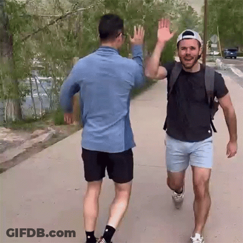 Two Men High Fiving On Sidewalk GIF