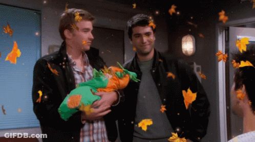 Two Men Holding Baby In Room With Falling Leaves GIF
