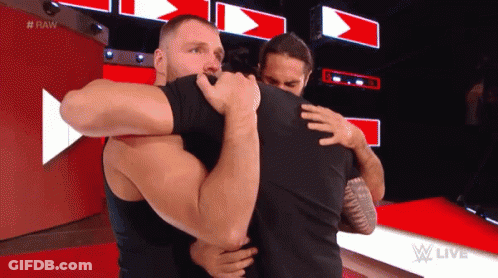 Two Men Hugging Each Other On A Red Carpet In Front Of A Red Wall . GIF