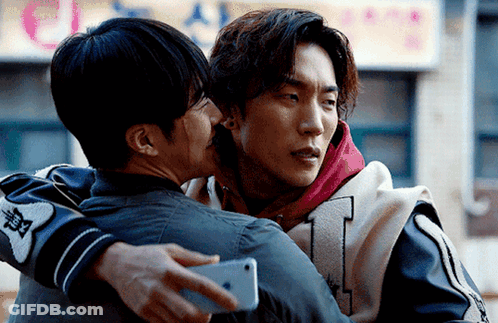Two Men Hugging Each Other With One Holding A Phone GIF