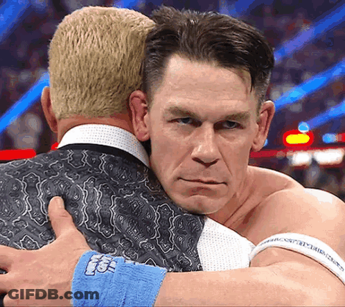 Two Men Hugging Each Other With One Wearing A Wristband That Says ' Tna ' GIF