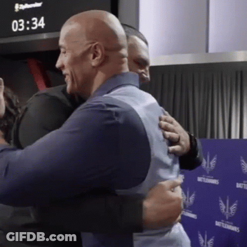 Two Men Hugging In Front Of A Wall That Says Battlehawks GIF