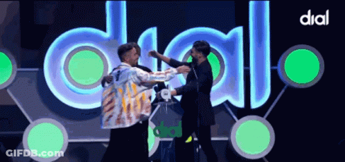 Two Men Hugging In Front Of Dial Sign GIF