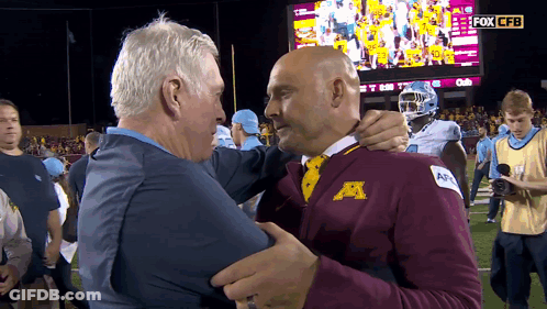 Two Men Hugging In Front Of Fox CFB Screen GIF