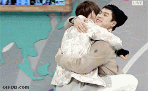 Two Men Hugging In Front Of Live Screen GIF