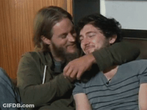 Two Men Hugging On Couch One Smiling GIF