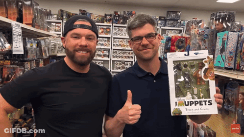 Two Men In A Store Holding A Box Of Muppets GIF