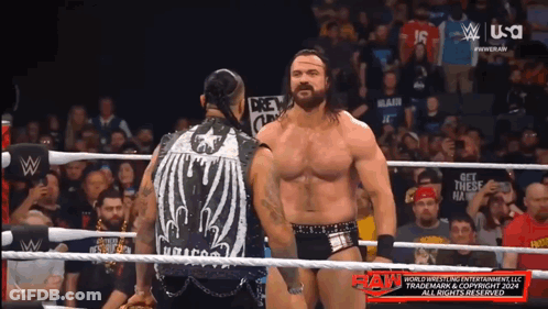 Two Men In A Wrestling Ring With A Sign That Says " Get These Hands " On It GIF