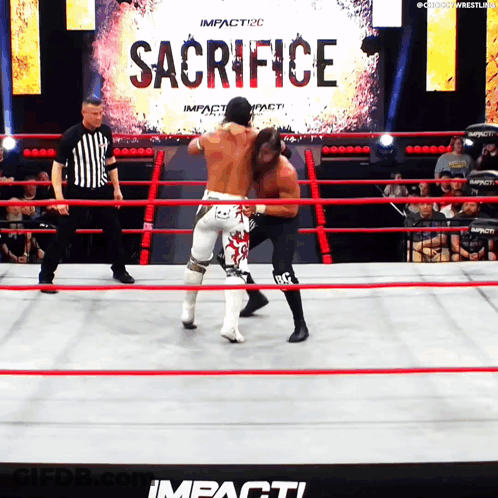 Two Men In A Wrestling Ring With A Sign That Says Sacrifice In The Background GIF