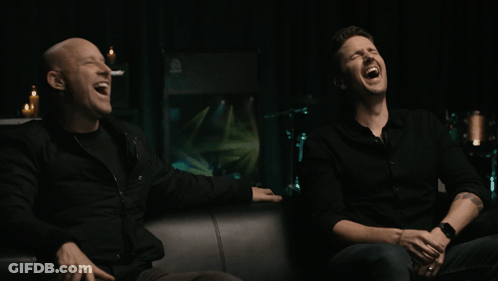 Two Men In Black Shirts Laughing Together GIF