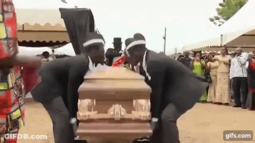 Two Men In Black Suits Dancing Around Coffin GIF