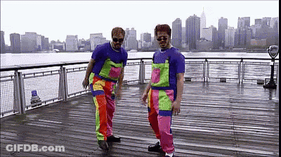 Two Men In Colorful Overalls Dancing On Pier GIF