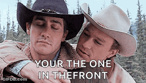 Two Men In Cowboy Hats Are Hugging Each Other With The Words `` Your The One In The Front '' Written Above Them . GIF