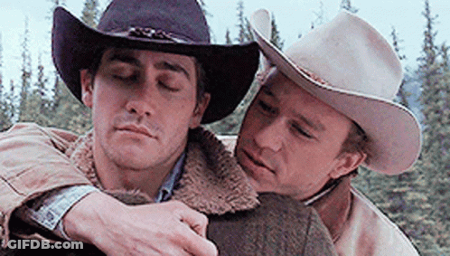 Two Men In Cowboy Hats Are Hugging Each Other With Their Eyes Closed . GIF