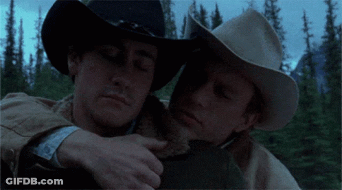 Two Men In Cowboy Hats Hugging Each Other In The Woods GIF