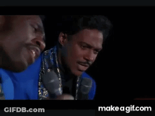 Two Men In Dark Room One Holding Microphone GIF