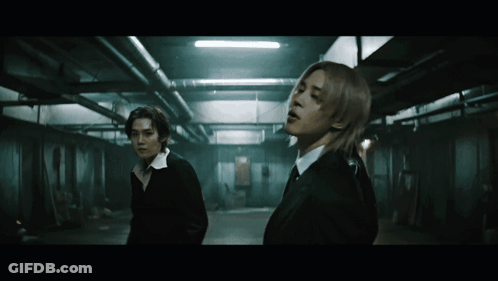 Two Men In Dark Room One With Long Hair GIF