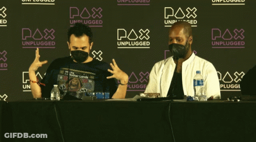 Two Men In Face Masks Sitting In Front Of Pax Unplugged Sign GIF