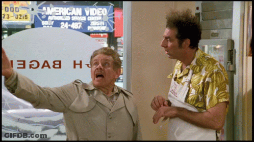 Two Men In Front Of An American Video Sign GIF