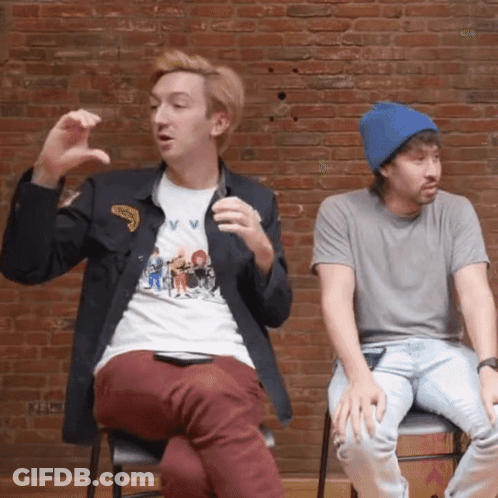 Two Men In Front Of Brick Wall One Wearing V V Shirt GIF