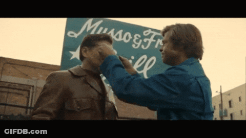 Two Men In Front Of Museos Sign GIF