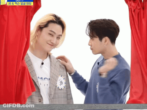 Two Men In Front Of Red Curtain One With JB Name Tag GIF