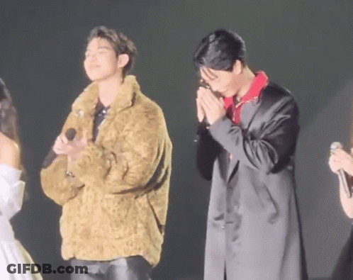 Two Men In Fur And Black Coats On Stage GIF