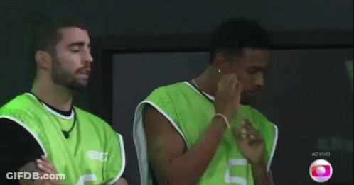 Two Men In Green Vests Are Standing Next To Each Other With Their Arms Crossed . GIF